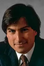 A smiling Steve Jobs in a black suit