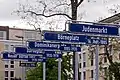 Five street signs show the chronological change of place names in the immediate vicinity