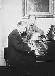 Stravinsky playing an upright piano, Furtwangler sitting beside him studying the score