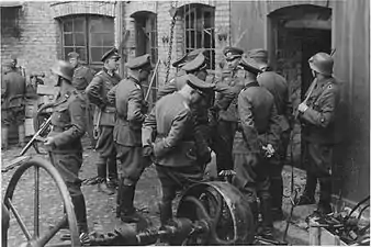 NARA copy #3, IPN copy #3Discussing the evacuation of the factoryGuard on the left is Josef Blösche. Herman Brauer helm repair shop at Nalewki 28–38. 24 April 1943