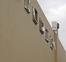 a number of white cockatoos are biting parts of the building wall, leaving chunks of polystyrene missing.