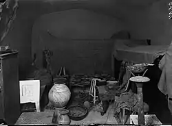 Plain-walled room densely packed with neatly arranged furniture and offerings