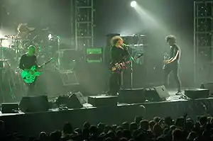 The Cure performing in August 2007; from left to right: Pearl Thompson, Jason Cooper, Robert Smith, and Simon Gallup