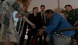 A man is attaches an artificial leg while people watch.