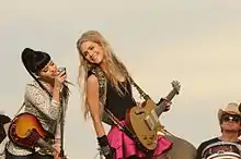 Two young woman performing while holding guitars