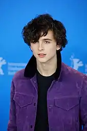 Timothée Chalamet standing in front of a blue background at the 67th Berlin International Film Festival in 2017