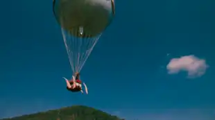 An American hot-air balloon ascends from a countryside to a clear sky.