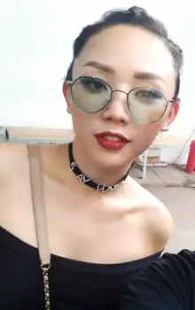 Tóc Tiên, wearing glasses and a black dress