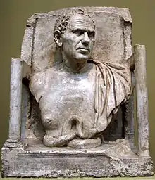 Photograph of a square sculpture showing the head and shoulders of a man, wearing a toga.