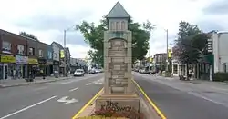 Stone marker in the middle of a road, marked 'The Kingsway'