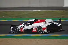 A side view of the Toyota TS050 Hybrid Le Mans Prototype 1 racing car with the number 7 inside a red triangle painted to the right of the front-left wheel