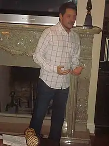 Country music singer Ty Herndon, standing before a fireplace