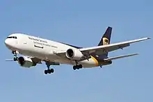 Side quarter view of UPS twin-engine freighter in flight, with extended gear