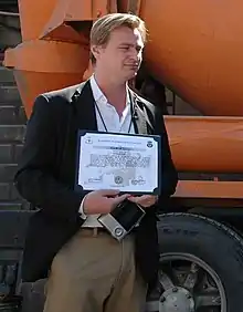 A middle-aged man holding a certificate from afar.