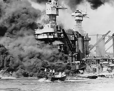 Hyperboloid mast towers were on the USS&nbsp;West Virginia aflame at Pearl Harbor on December 7, 1941, and a small boat rescues a seaman.