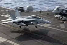 Jet aircraft with landing gear extended flying in a nose-high attitude.