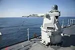 Mk 38 MOD 2 25mm autocannon gun system aboard the amphibious dock landing ship USS&nbsp;Pearl Harbor forward ejecting the spent casings.