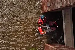 A Coast Guard Aviation Survival Technician assisting with the rescue of a pregnant woman during Hurricane Katrina in 2005