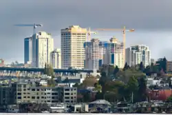 The U District, looking northeast from South Lake Union, showing recent tower development alongside the older UW Tower and Graduate Hotel. The I-5 Ship Canal Bridge is in the midground, and floating houses in Eastlake are in the foreground.