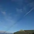 Shadow cast by vapor trail of passing aircraft