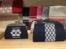 Two small indigo purses decorated with a central stripe of dense white embroidery.