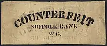 A rectangular piece of paper. Counterfeit is printed on the top. "Suffolk Bank" is in the middle, above "WG"