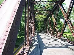 A photo (taken in daytime) of some of a bridge which is near vegetation