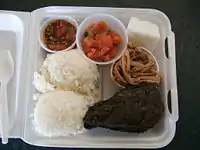 Traditional Hawaiian plate lunch. Clockwise, from bottom left: two scoop white rice, ahi poke, lomi-lomi salmon, haupia dessert, kālua puaʻa (roast pork), and pork laulau.