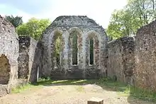 grey stone walls leading to an end wall with three tall window openings