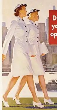 Two WAVES women in summer dress uniforms walking side by side down a city street