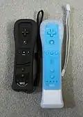 A black Wii Remote Plus in a black jacket next to a blue Wii Remote and white Wii MotionPlus