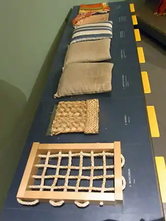 Museum samples demonstrating a 1590s bed: the bedcords, bedmat, three tick mattresses in dun and striped ticking, and the bedlinen.
