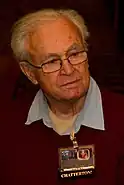 An 87-year-old man with white hair and glasses looking to the right of the camera.