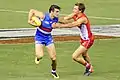 Easton Wood applies a fend to the chest of Will Hayward during an Australian rules game.