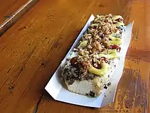 A zapiekanka topped with ketchup, mustard and chopped, browned onions