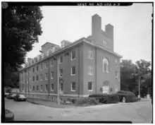 A photograph of a four-and-a-half-story brick building with a pitched room and two chimneys on its near end
