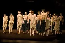 Dancers in raggedy white clothes surrounding "The Chosen One", who is kneeling