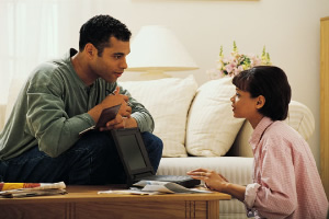 man and woman paying bills at coffee table