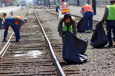 Responders cleaning around railroad tracks at a disaster site.