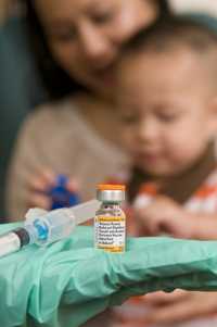 Photo of mother holding baby son for vaccination.