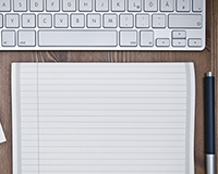 photo of a keyboard, pencil and notepad