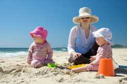 Photo of a mother and two young children at the beach