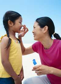 Photo of a woman putting sunscreen to her young daughter.