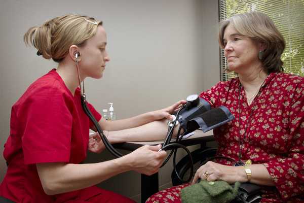 Woman seated having her blood pressure taken.
