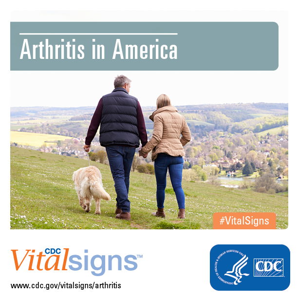 A couple walking a dog on a grassy hillside