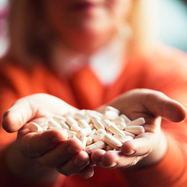 Hands holding a pile of pills