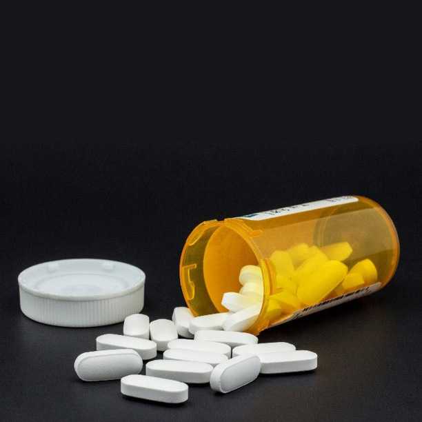White, oblong pills spilled from a prescription bottle.