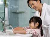 Mother teaching daughter to wash hands