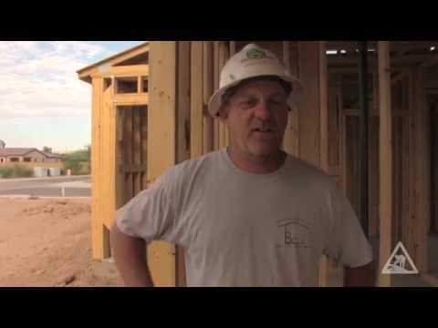Construction worker in front of a wood building frame