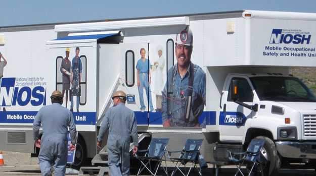 Two miners approach a NIOSH mobile health unit